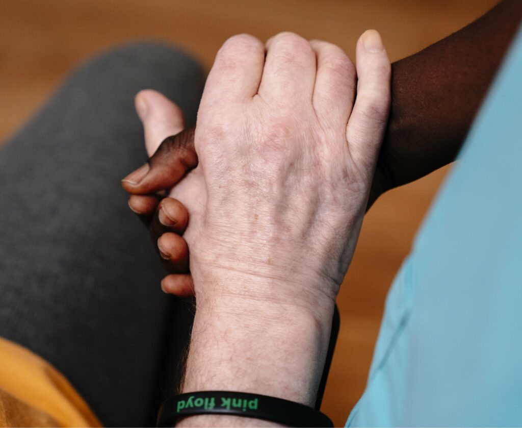 Eine Sentio-Mitarbeiterin hält die Hand einer Patientin